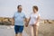 Happy retired mature couple walking on the beach - pensioner woman and her husband taking romantic walk together enjoying sweet