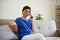 A happy retired middle-aged woman is on the phone with someone while sitting on a cozy sofa