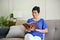 A happy retired middle-aged woman is reading a book while relaxing on a sofa