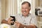 Happy Retired Senior Man Sitting On Sofa At Home Looking At Photograph