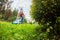 Happy retired senior person mows a lawn in his garden with a lawnmower. Garden work.