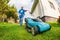 Happy retired senior person mows a lawn in his garden with a lawnmower. Garden work.