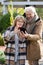 Happy retired spouses in warm casualwear looking at their family in smartphone