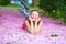 Happy roller girl lying in pink petals, spring garden