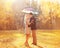 Happy romantic kissing couple in love with colorful umbrella together at warm sunny day over yellow flying leafs
