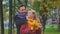 Happy romantic young couple with a man holding woman form behind standing in the golden autumn park enjoying the