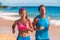 Happy running competitive couple smiling training together on summer beach. Asian fitness model, Caucasian male runner