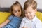 happy and sad little cute preschool siblings baby boy and child girl talk video conference by smartphone in living room