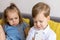 happy and sad little cute preschool siblings baby boy and child girl talk video conference by smartphone in living room