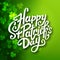 Happy Saint Patrick\'s day handwritten message, brush pen lettering on blurred green shamrock background postcard