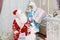 Happy Santa Claus and beautiful granddaughter are sitting indoors in the New Year`s interior and holding New Year`s