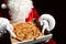 Happy Santa Claus hold big hot steaming pizza offering with copy space. New year and Xmas fast food