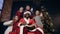 Happy santa claus in red hat and cute four kids waving to the camera.