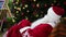 Happy Santa Claus waving hand in rocker chair to welcome shopping mall visitors