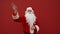 Happy Santa stands on a background of a red wall and is greeted with a smile on his face. Positive Santa on a red background