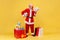 Happy satisfied elderly man wearing santa claus costume standing holding soccer ball and fan of money, betting and win, buy