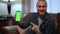Happy satisfied man showing green screen phone pointing smiling looking at camera. Portrait of Caucasian gamer posing