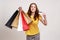 Happy satisfied teenager girl in yellow T-shirt holding and showing limitless credit card and shopping bags, happy with great