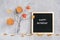 Happy Saturday text on black letter board and bouquet of branches with yellow leaves on clothespins in vase on table Template for