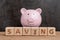 Happy savings, budget, investment or financial goals concept, smile pink piggy bank and stack of cube wooden block building word