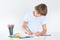 Happy school boy paiting at a white desk