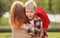 Happy schoolboy with backpack hugging embracing his mother before going to school on sunny day