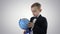 Happy schoolboy in a formal suit studying a globe on gradient background.