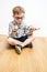 Happy schoolboy having doubt over picking many eyeglasses, wooden floor