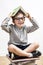 Happy schoolboy with missing tooth covering his head with book