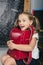 Happy schoolchild in the classroom with big backpack