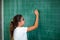 Happy schoolchild writing on blackboard.