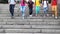 Happy schoolchildren run down stone stairs on sunny day