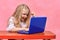 Happy schoolgirl behind laptop shows gesture idea. online training. concept