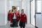 Happy schoolgrirl with Down syndrome in uniform walking in school corridor with her classmate, holding each other hands.
