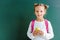 happy schoolkid holding apple on green .