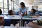 Happy schoolkids talking with teacher at desk in classroom