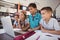 Happy schoolkids using laptop in library