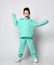 Happy screaming kid boy in modern green, mint color hoodie, pants and white sneakers stands holding hands inside sleeves