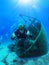 A happy Scuba diver explores a sunken shipwreck in the mediterranean sea