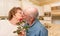 Happy Senior Adult Man Giving Red Rose to His Wife In a Kitchen