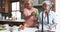 Happy senior african american female friends cooking in kitchen, washing vegetables, slow motion