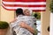 Happy senior african american woman embracing soldier son on his return home at entrance