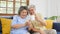 Happy senior asian couple using smart phone while sitting on sofa at home living room background, active senior people retirement