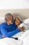Happy senior biracial couple lying in bed embracing at home