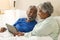 Happy senior biracial couple lying in bed using tablet at home