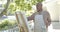 Happy senior biracial man painting at balcony at home, slow motion