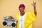 Happy senior black woman with traditional african dress dancing holding boombox stereo - Focus on face