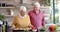 Happy senior caucasian couple cooking dinner in kitchen at home, slow motion