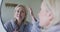 Happy senior caucasian woman in bathroom, looking to mirror, touching face