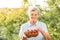 Happy senior caucasian woman picking up strawberries in the garden during the sunset or sunrise. Elderly lady farmer with grey